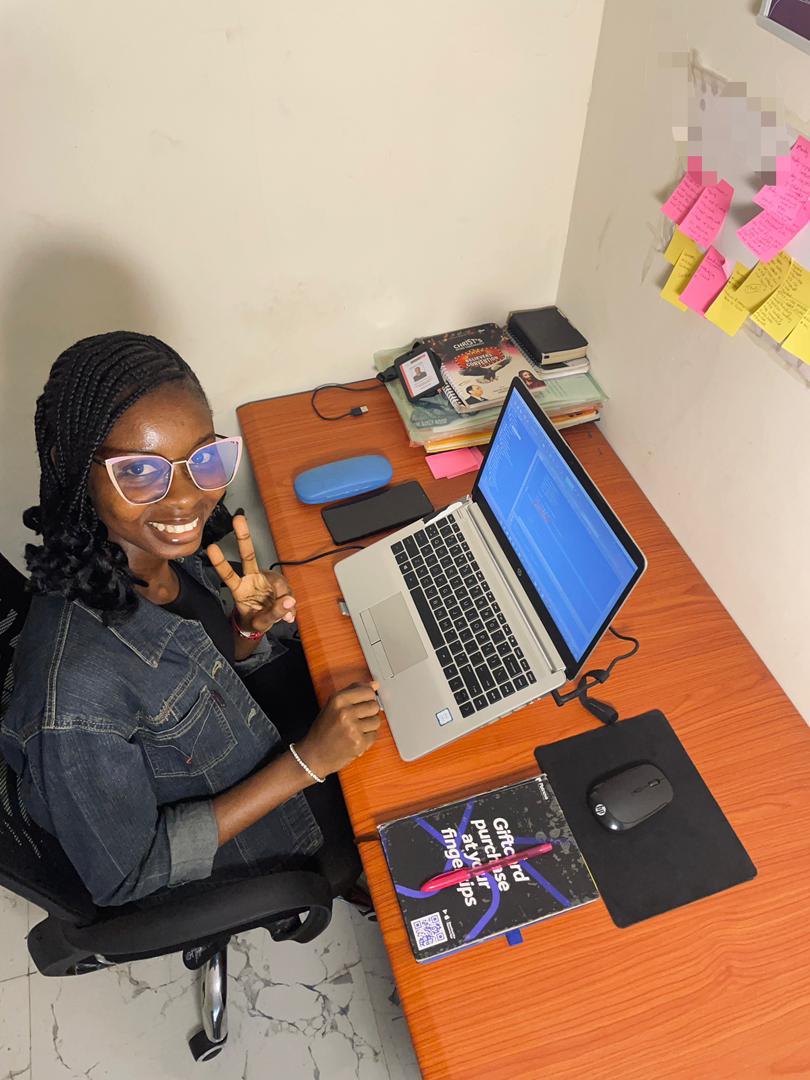 Marvelous Rose smiling at a desk with a laptop and sticky notes